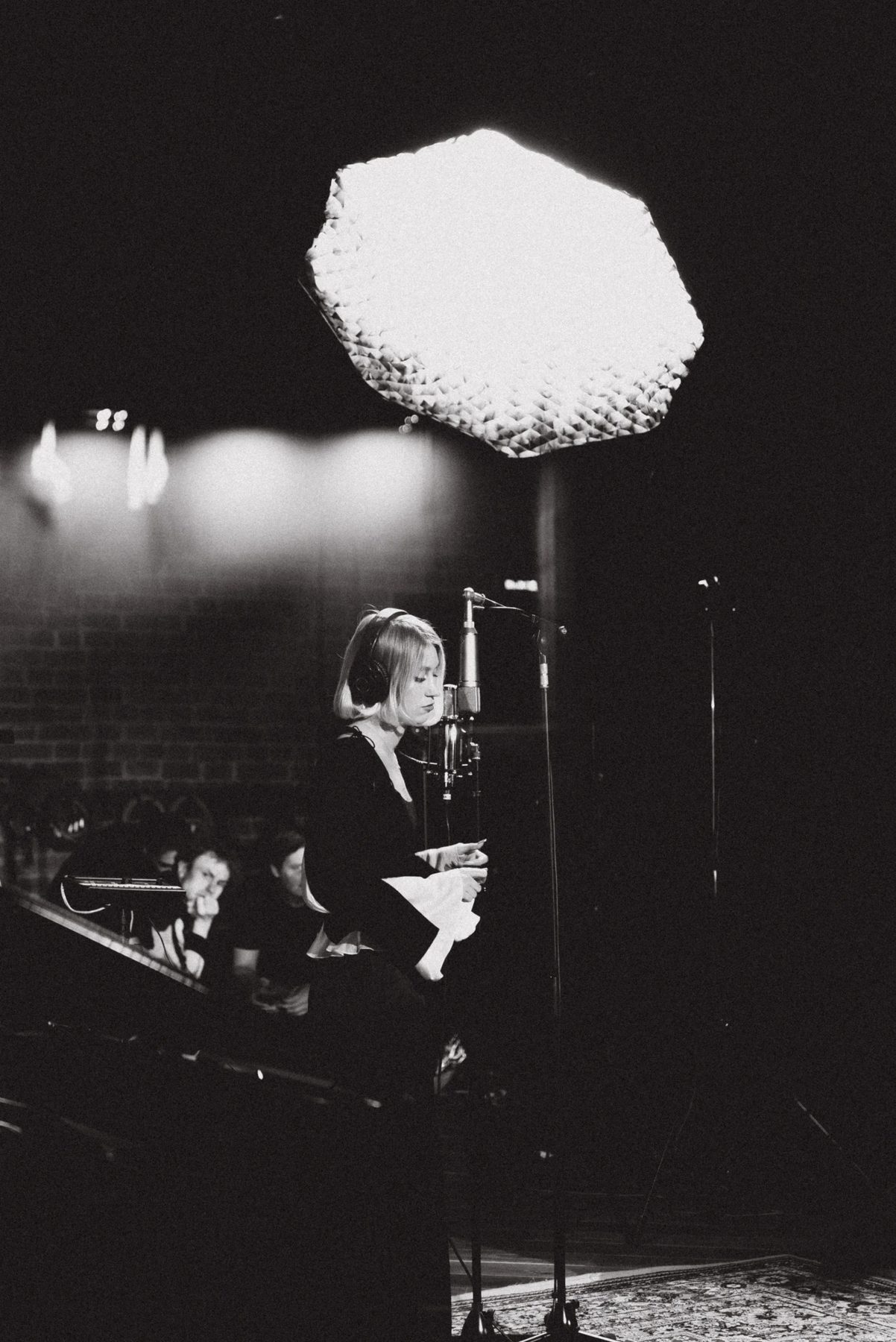 Ari singing at the microphone, black and white